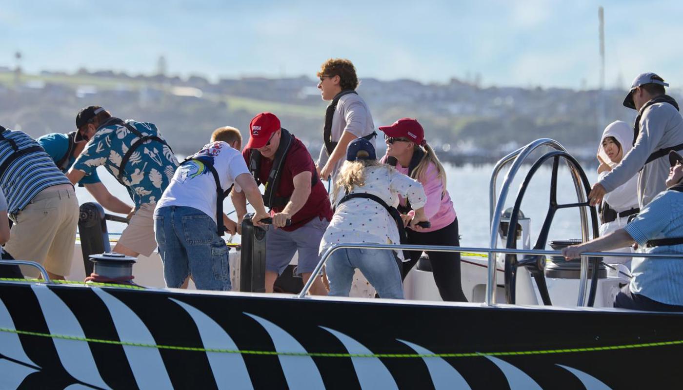 Passengers working the grinders on an America's Cup Sailing Experience.